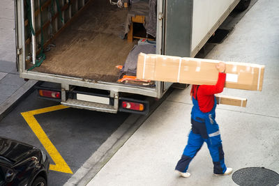 High angle view of delivery man with box walking on road