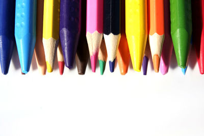 Close-up of colored pencils over white background