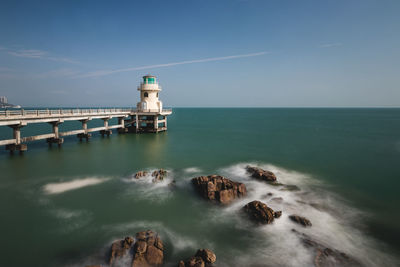 Lighthouse by sea against sky