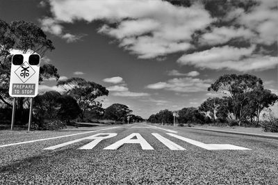 Road sign by trees against sky