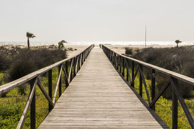 Wooden footbridge on footpath against clear sky