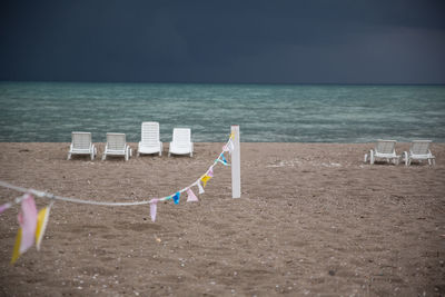 Chairs on beach against sky