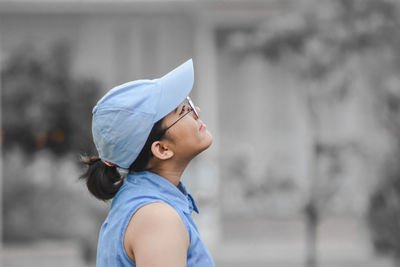 Close-up of teenager girl in casual clothing with hat standing and looking up 