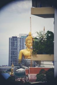 Statue by buildings against sky in city