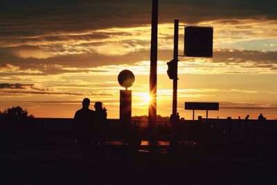 Silhouette people by sea against sky during sunset