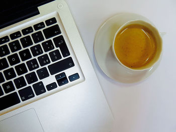 High angle view of coffee by laptop on table