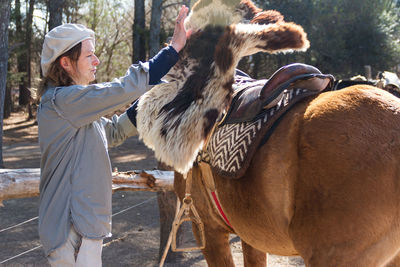 Side view of woman with horse standing outdoors