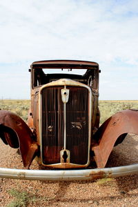 Close-up of rusty car on field against sky