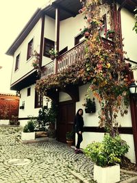 Woman standing by potted plant against building