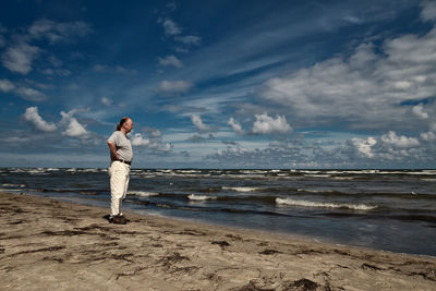 Full length of man standing on beach against sky