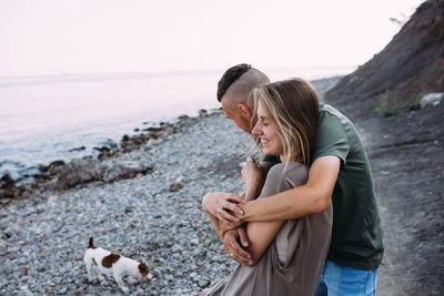 Happy couple with favourite pet. young man and woman have walk near sea.