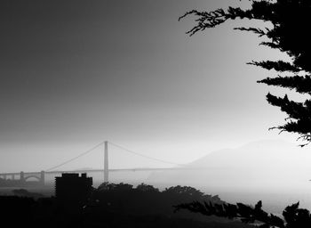 Silhouette of suspension bridge against sky