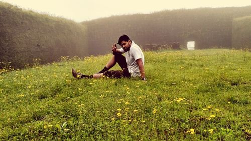 Young man sitting on grassy field