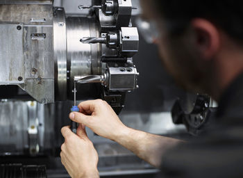 Technician repairing drill bit on metal machine in factory