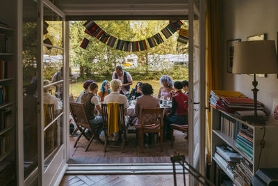 Happy friends of lgbtq community enjoying during dinner party in back yard seen through doorway