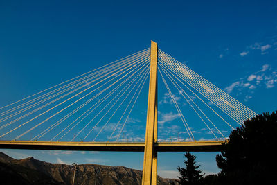 Low angle view of suspension bridge against clear blue sky