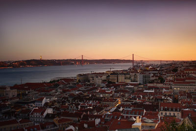 High angle view of river and buildings against sky at sunset