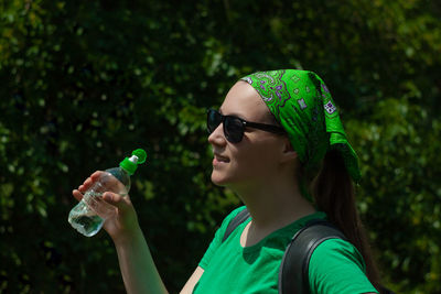 Young girl holds a bottle of water in hand and drinks weight loss, summer active lifestyle body care