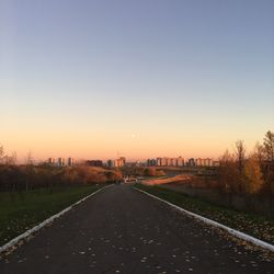 Road in city against clear sky during sunset