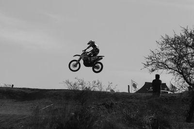 Man riding bicycle on field against sky