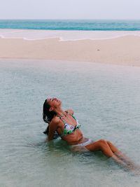 Young woman in bikini sitting in sea