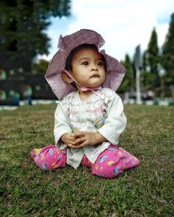 Cute baby girl sitting on grass in field