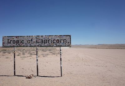 Information sign on desert against clear blue sky