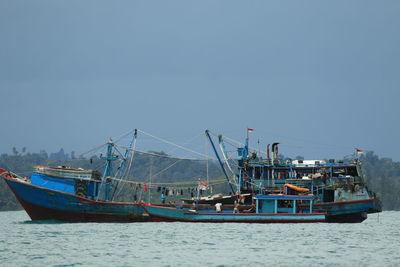 Fishing boats in sea against clear sky