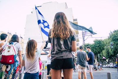 Rear view of people watching flags against clear sky