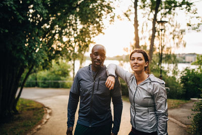 Portrait of confident male and female athletes standing on road in park