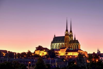 Illuminated church in city against clear sky during sunset