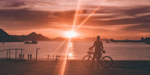 Silhouette people at beach against sky during sunset