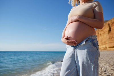 Low section of woman on beach against sky