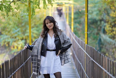 Young woman standing against railing