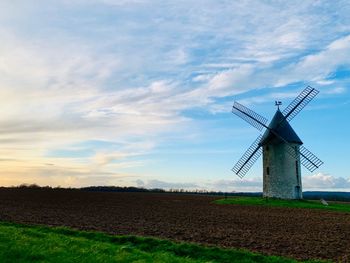 Traditional windmill on field against sky