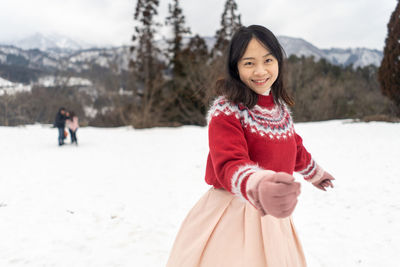Portrait of smiling young woman standing on snow covered land