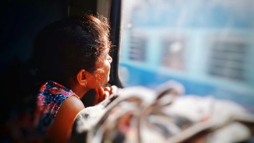 Side view of woman looking through train window