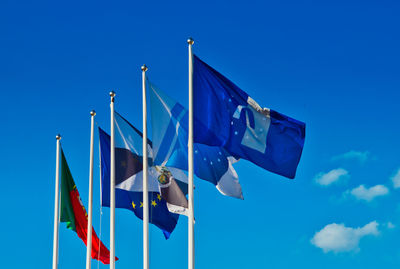 Low angle view of flags against blue sky