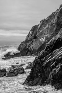 Rock formation on beach against sky