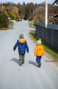 Rear view of boy walking on road