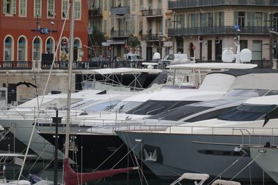 Sailboats moored on harbor by buildings in city