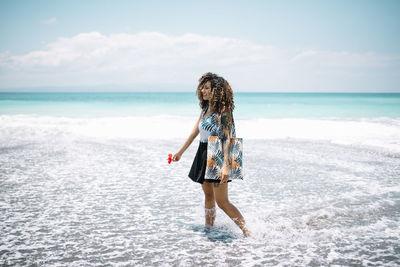 Woman with curly hair standing at beach