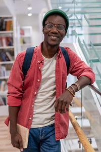 Portrait smiling happy african american student hipster guy with books in campus university library