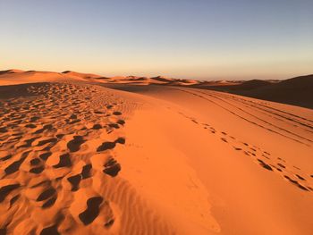 Scenic view of desert against clear sky during sunset