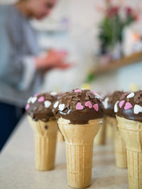 Close-up of ice cream cones on counter with woman standing in kitchen