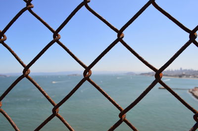 Scenic view of sea seen through chainlink fence