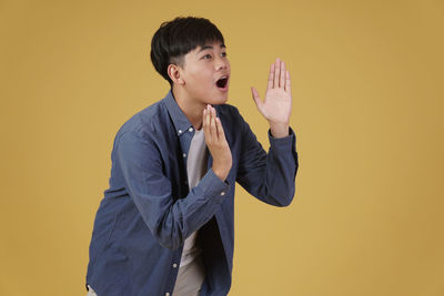 Mid adult man standing against yellow background