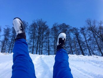 Low section of man on snow field against clear blue sky