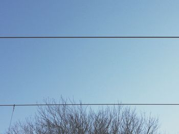 Low angle view of power lines against clear blue sky