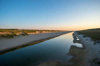 Scenic view of lake against clear sky during sunset